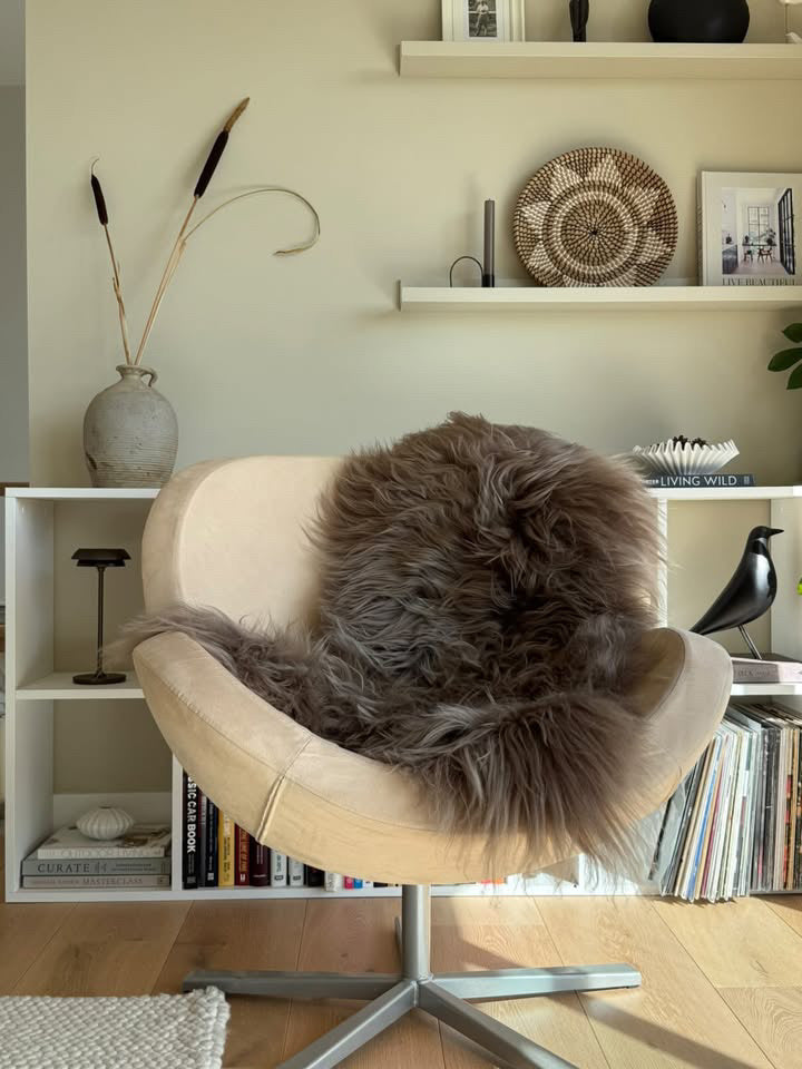 brown long hair sheepskin rug on a chair infront of shelves