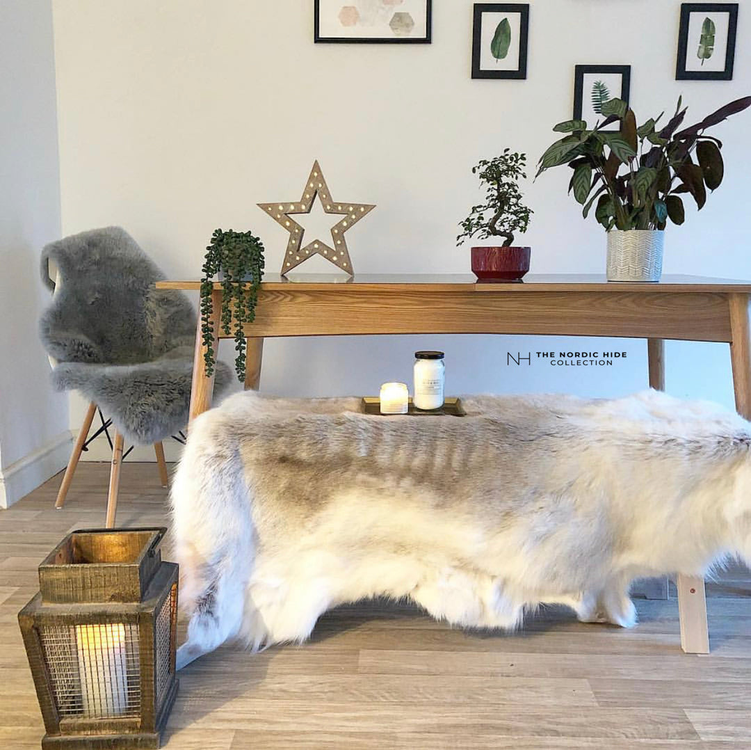 grey and white reindeer rug on a bench in a room with grey painted walls 