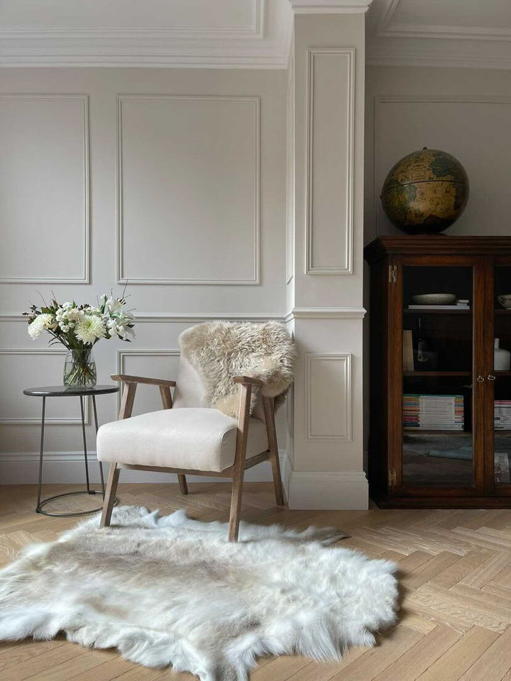 reindeer hide on floor next to a chair with an oyster sheepskin rug 