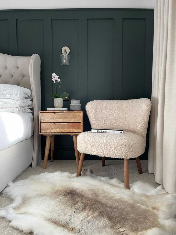 reindeer hide on floor next to a bed 