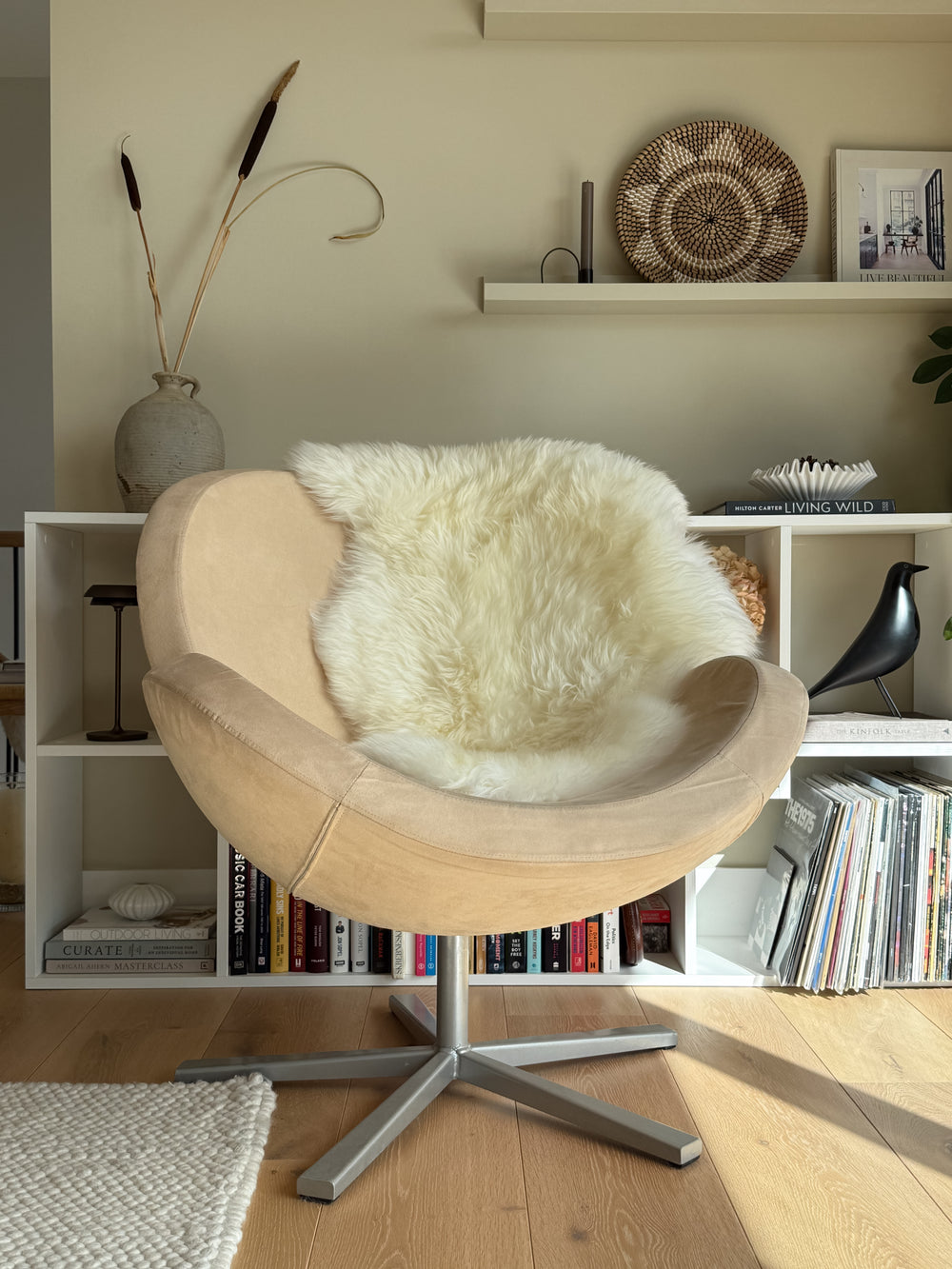 Wooden chair with a white fur cover in a room with a bookshelf.
