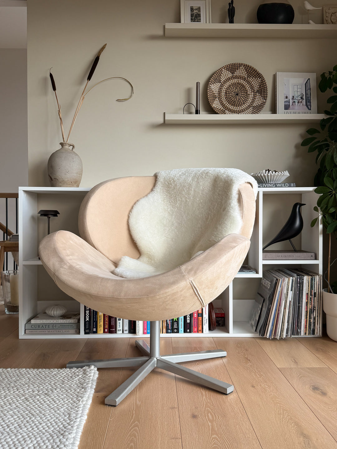 Beige armchair in a living room with bookshelves and decor items.