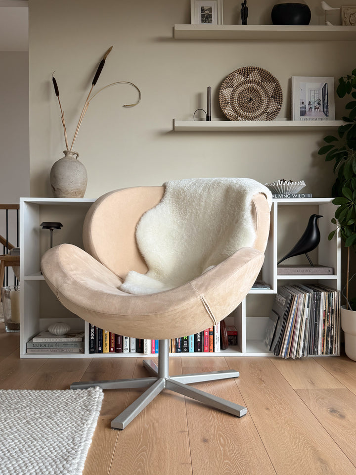 Beige armchair in a living room with bookshelves and decor items.