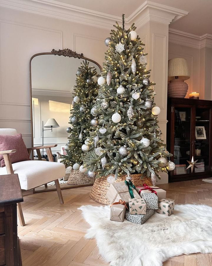 Decorated Christmas tree with ornaments and presents in a living room.