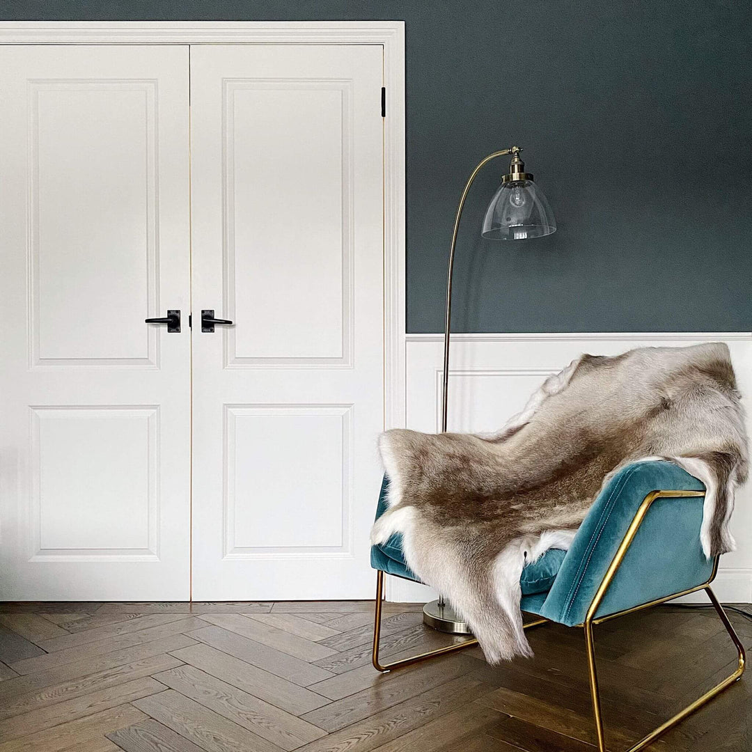 Authentic reindeer hide rug styled in Scandinavian interior on turquoise chair 