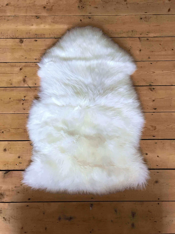 white sheepskin lay flat on a wooden floor 